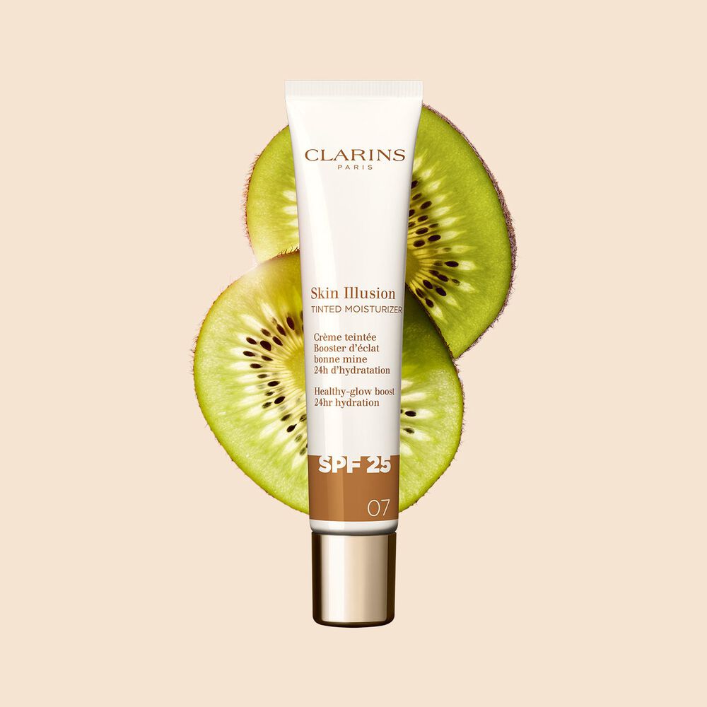 Plan produit du tube de 40 ml du perfecteur de teint Skin Illusion Tinted Moisturizer teinte 07, placé à côté de tranches de kiwi.