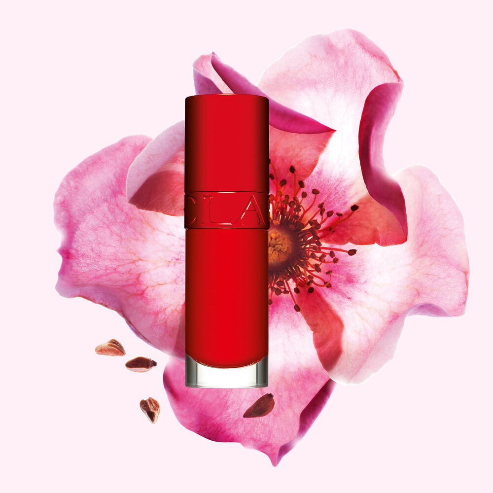 Plan produit de l&rsquo;Huile Confort L&egrave;vres Clarins en teinte Iconic Red avec une rose musqu&eacute;e sur fond rouge et noir.