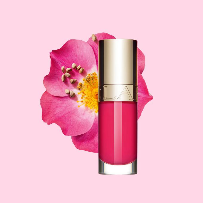 Plan produit de l’huile lèvre rose Clarins devant une fleur de rosier rouillé sur fond blanc