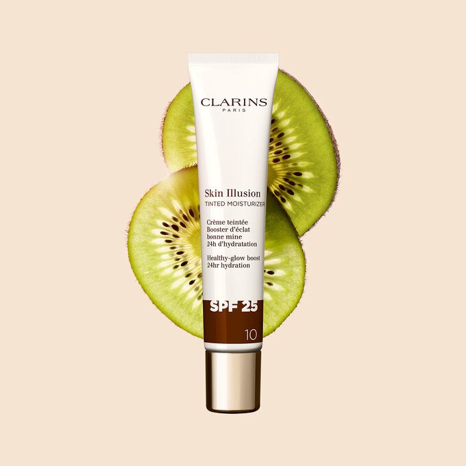 Plan produit du tube de 40&nbsp;ml du perfecteur de teint Skin Illusion Tinted Moisturizer teinte&nbsp;10, plac&eacute; &agrave; c&ocirc;t&eacute; de tranches de kiwi.