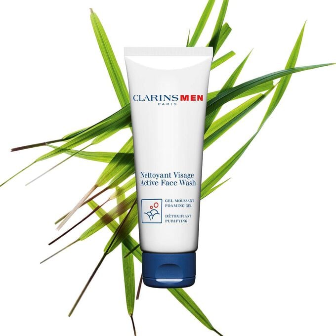 Plan produit du Nettoyant Visage, nettoyant Clarins pour homme entour&eacute; d'herbe aux bisons pour mettre en valeur son ingr&eacute;dient cl&eacute;.