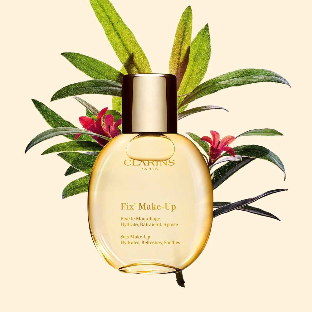Plan produit du spray fixateur de maquillage Fix’ Make Up Clarins positionné au-dessus d’un bouquet de rosiers des Alpes sur fond jaune clair