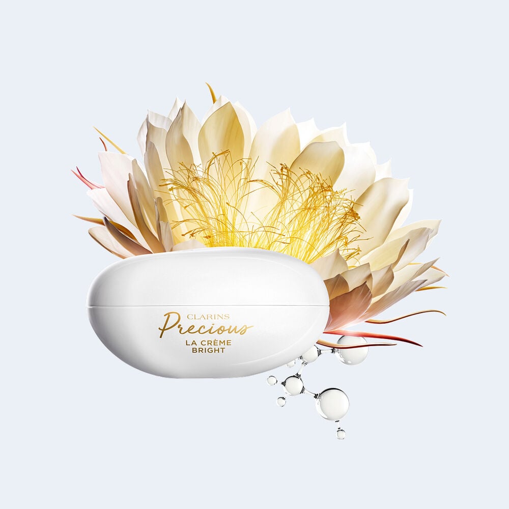 Plan produit de la Cr&egrave;me Bright Clarins Precious, entour&eacute;e de reine de la nuit et de mol&eacute;cules de peptide, ingr&eacute;dients cl&eacute;s pour l&rsquo;&eacute;clat.