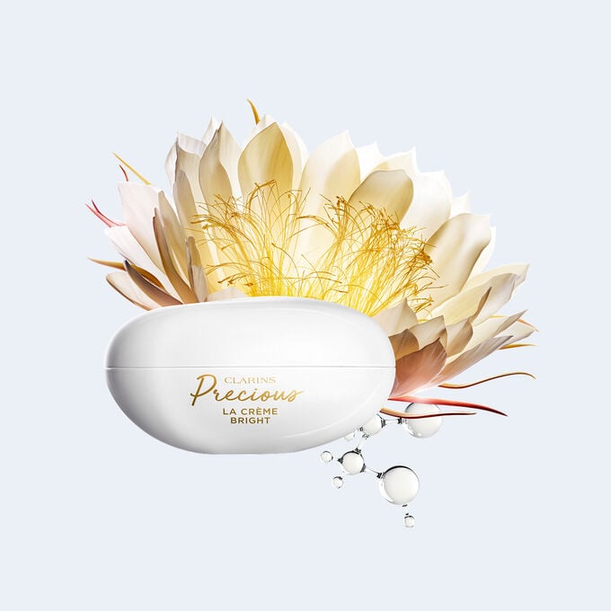 Plan produit de la Cr&egrave;me Bright Clarins Precious, entour&eacute;e de reine de la nuit et de mol&eacute;cules de peptide, ingr&eacute;dients cl&eacute;s pour l&rsquo;&eacute;clat.