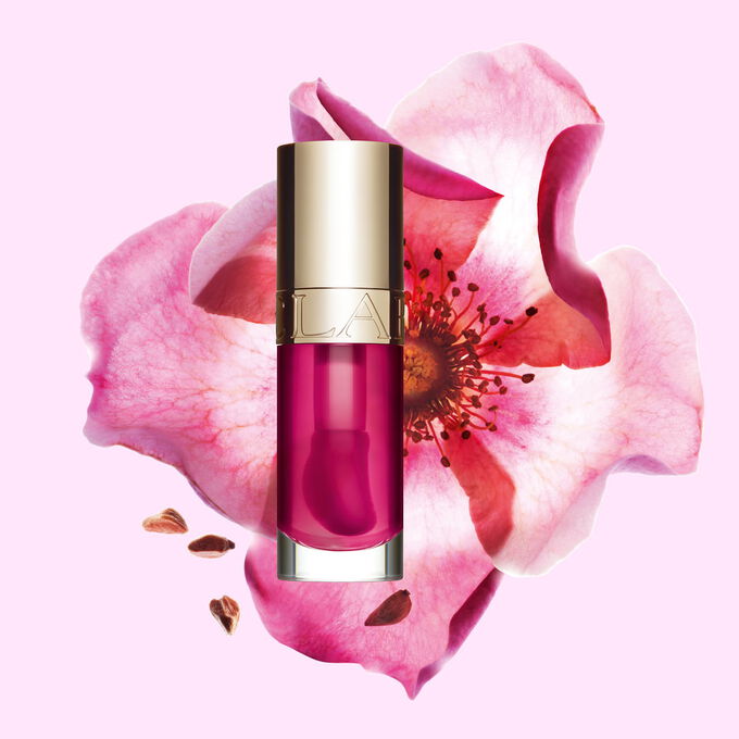 Plan produit de l&rsquo;Huile Confort L&egrave;vres Clarins en teinte Raspberry avec une rose musqu&eacute;e sur fond couleur p&ecirc;che clair.