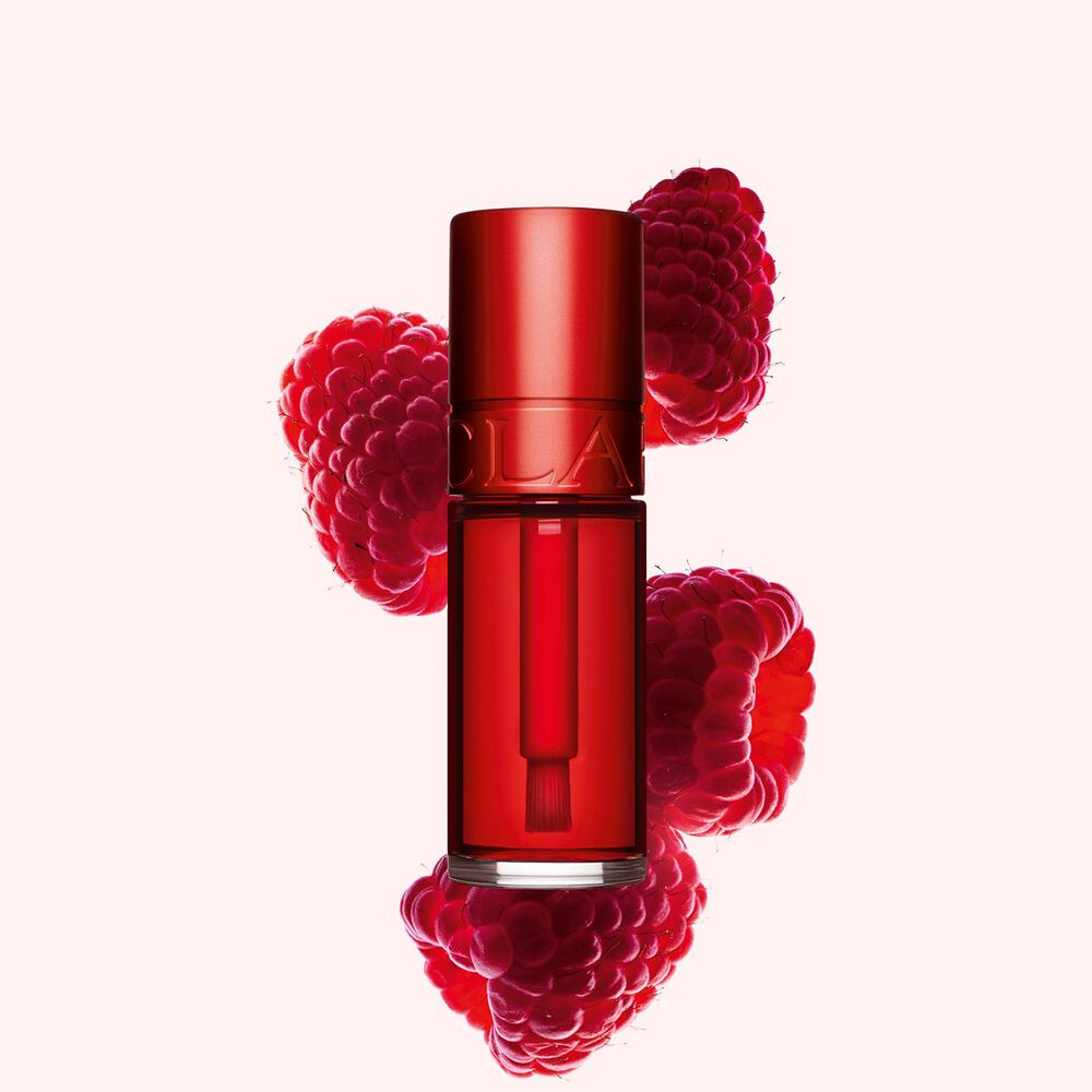 Plan produit de Water Lip Stain Rouge de Clarins en teinte 03, à côté de framboises sur fond rose clair.