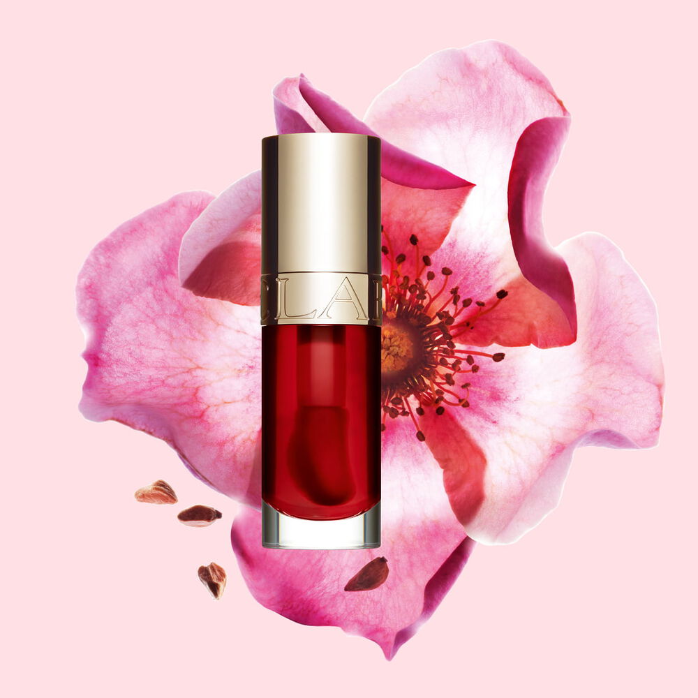 Plan produit de l&rsquo;Huile Confort L&egrave;vres Clarins en teinte Strawberry avec une rose musqu&eacute;e sur fond couleur rose clair.