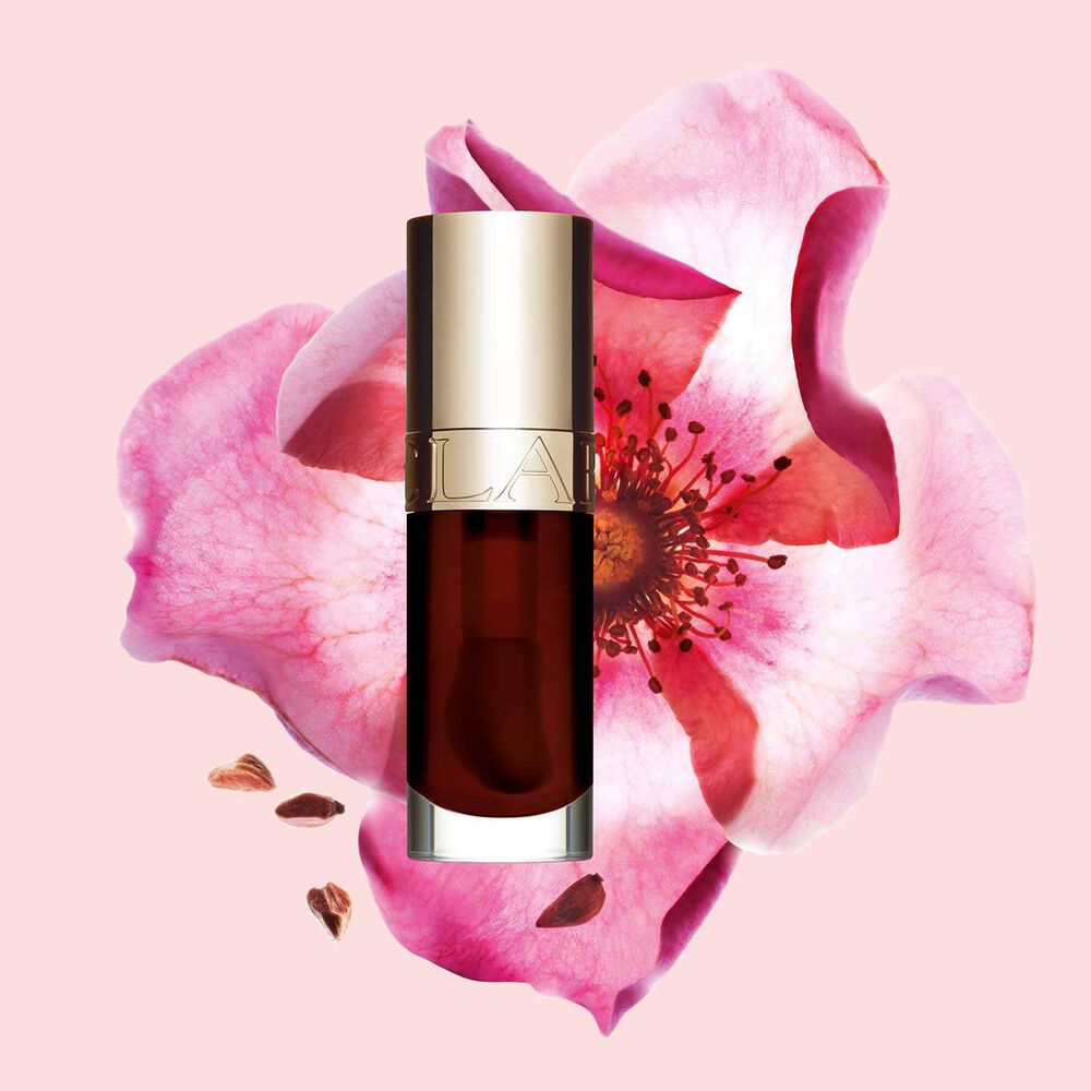 Plan produit de l’Huile Confort Lèvres Clarins en teinte Chocolate avec une rose musquée sur fond couleur rose clair.