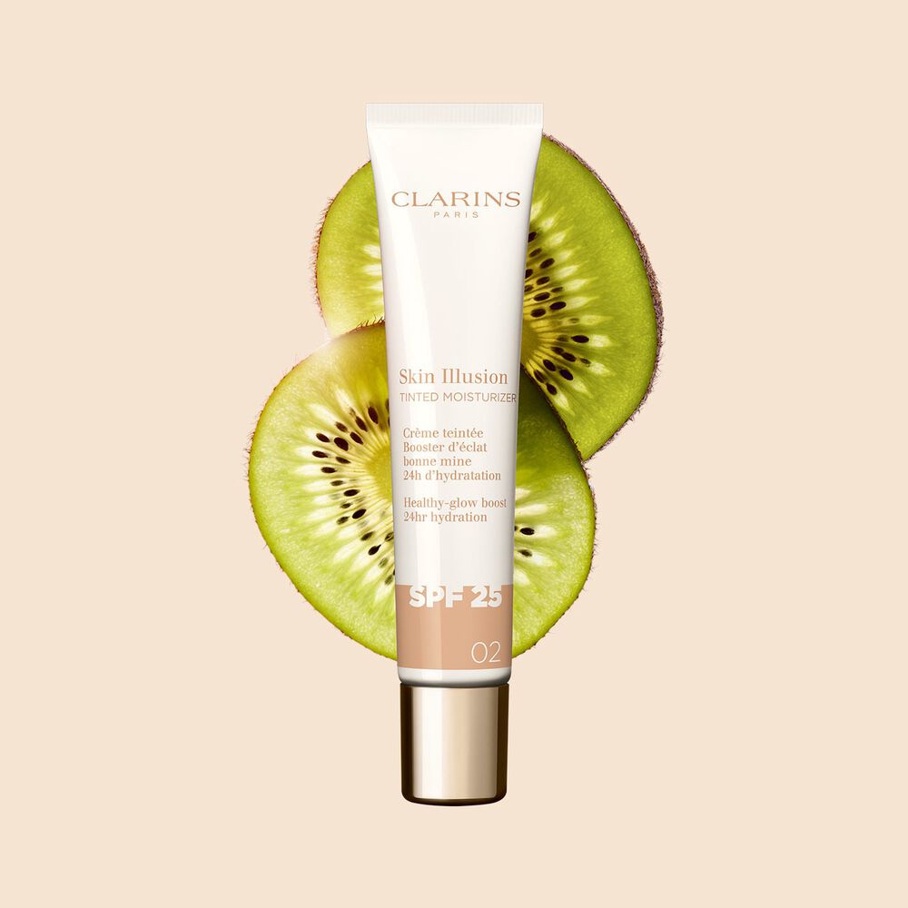 Plan produit du tube de 40 ml du perfecteur de teint Skin Illusion Tinted Moisturizer teinte 02, placé à côté de tranches de kiwi.