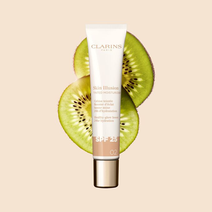 Plan produit du tube de 40 ml du perfecteur de teint Skin Illusion Tinted Moisturizer teinte 02, placé à côté de tranches de kiwi.