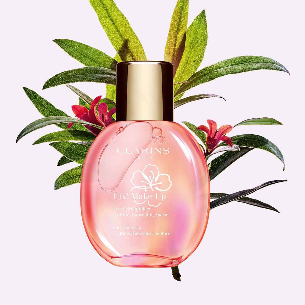 Plan produit d'un flacon de spray Fix' Make-Up Clarins à côté d'un bouquet de roses des Alpes pour mettre en valeur son ingrédient clé.