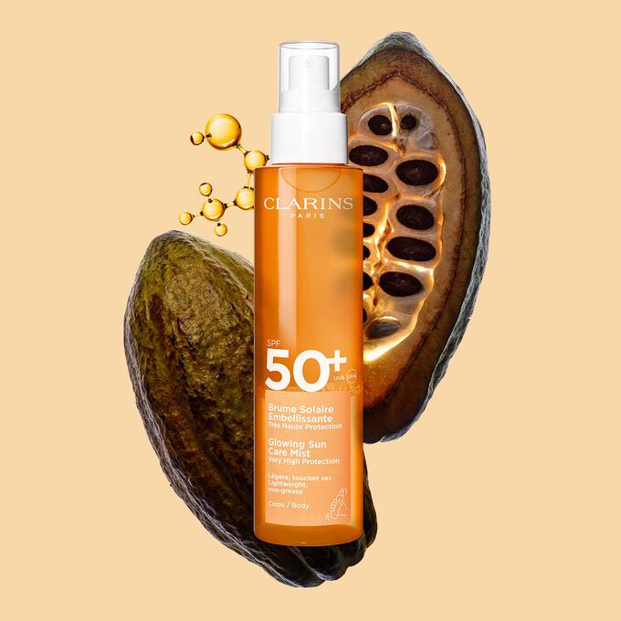 Plan produit de la Brume solaire &eacute;clat SPF 50 Clarins, un spray invisible, devant une mol&eacute;cule de collag&egrave;ne et des f&egrave;ves de cacao.