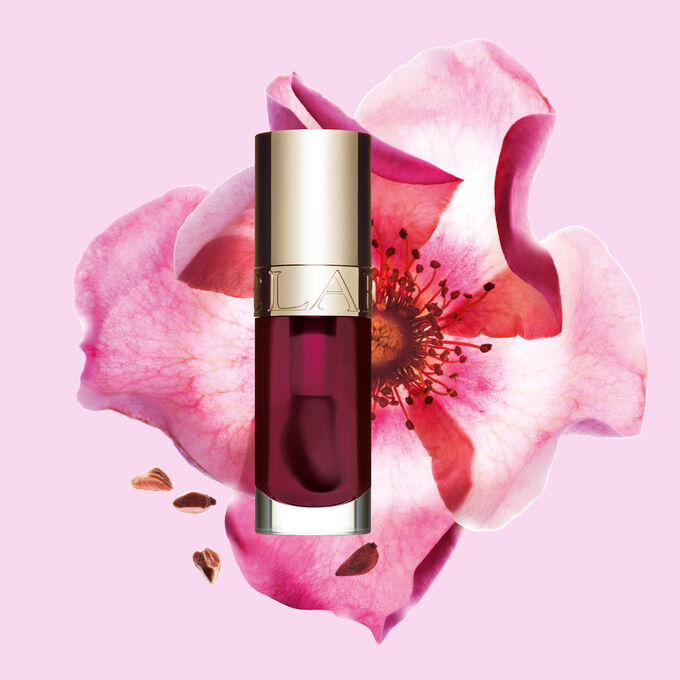 Plan produit de l&rsquo;Huile Confort L&egrave;vres Clarins en teinte Fig avec une rose musqu&eacute;e sur fond couleur rose clair.