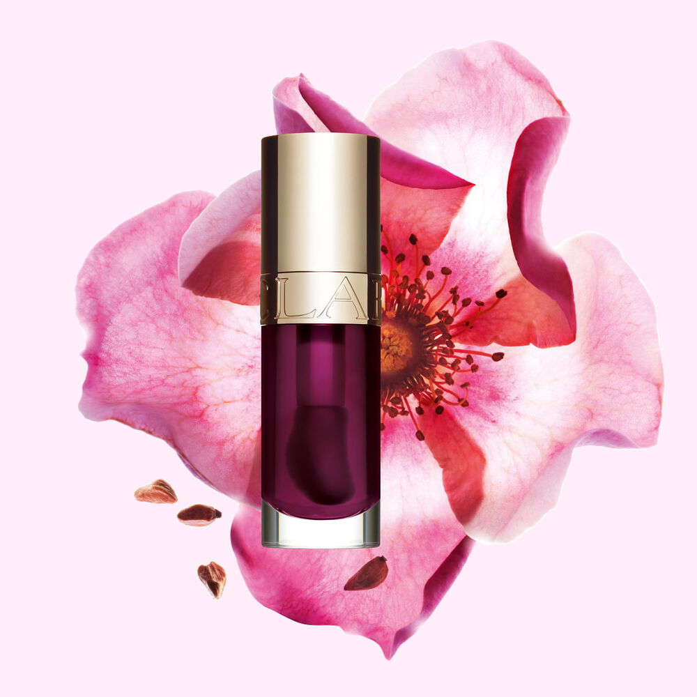 Plan produit de l&rsquo;Huile Confort L&egrave;vres Clarins en teinte Plum avec une rose musqu&eacute;e sur fond couleur rose clair.