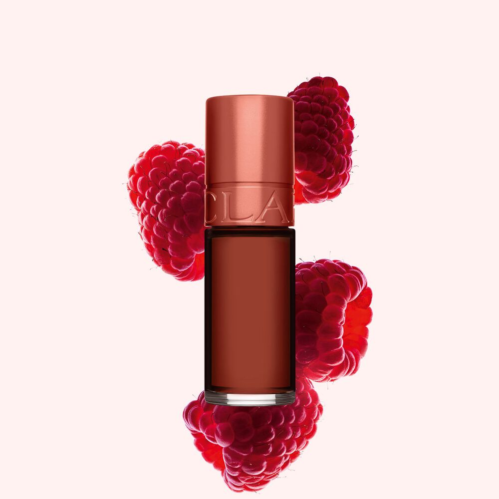 Plan produit de Water Lip Stain Marron de Clarins en teinte 13, à côté de framboises sur fond rose clair.
