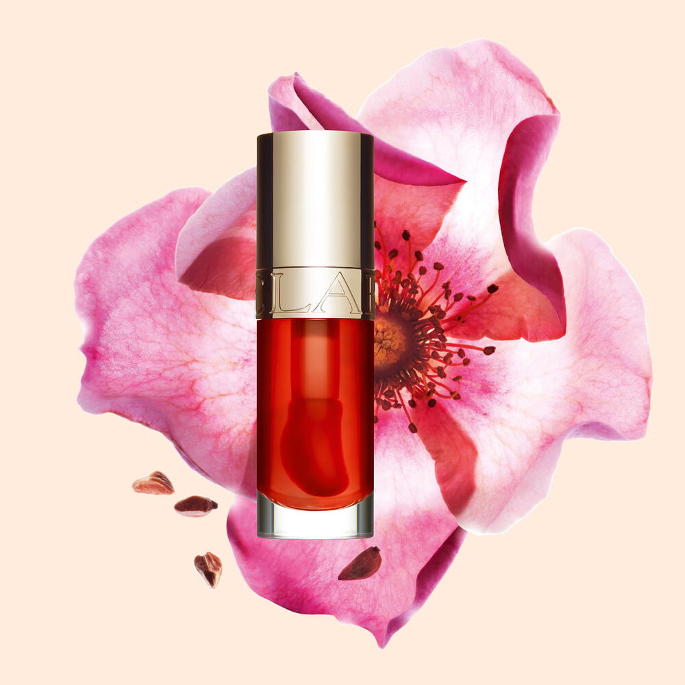 Plan produit de l&rsquo;Huile Confort L&egrave;vres Clarins en teinte Apricot avec une rose musqu&eacute;e sur fond couleur orange-p&ecirc;che clair.