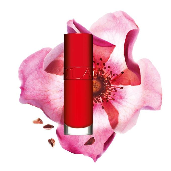 Plan produit de l’Huile Confort Lèvres Clarins en teinte Iconic Red avec une rose musquée sur fond rouge et noir.