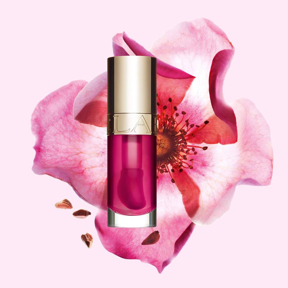 Plan produit de l’Huile Confort Lèvres Clarins en teinte Raspberry avec une rose musquée sur fond couleur pêche clair.