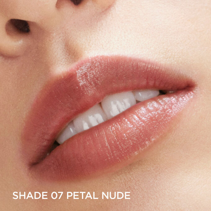 Gros plan sur les lèvres d'une femme portant le Lip Oil Balm Floraison Féerique Clarins, teinte Petal Nude, pour illustrer ses bienfaits lissants.