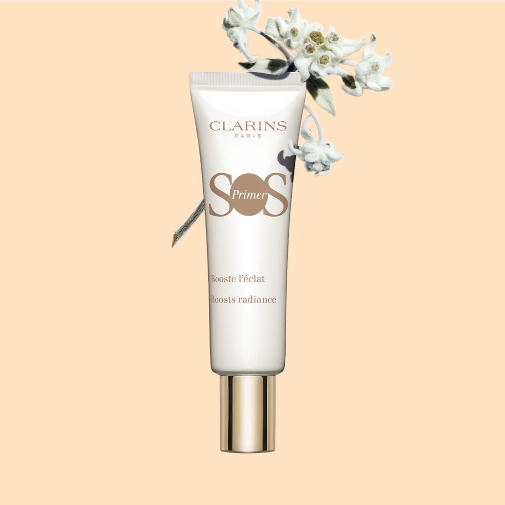 Plan produit tube SOS Primer Blanc de Clarins avec fleurs d’edelweiss, pour renforcer l'éclat et stimuler la luminosité.